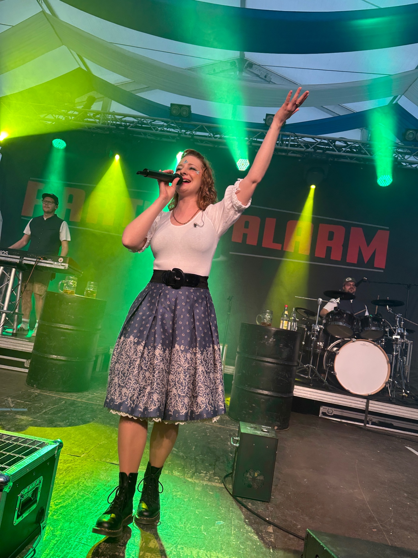 Sängerin von Partyalarm vor dem Bandbanner in grünem Licht